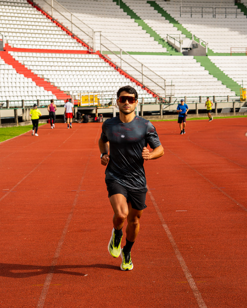 Corredor usando jersey Running Ultimate negro para hombre en pista.
